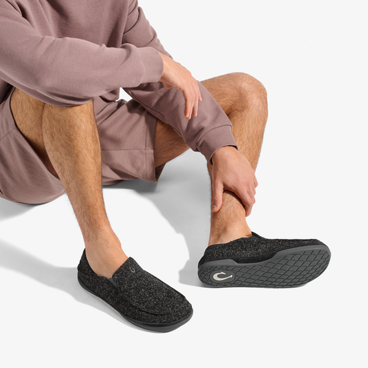 Black heathered slip-on slipper with textured sole, worn with mauve sweatpants.