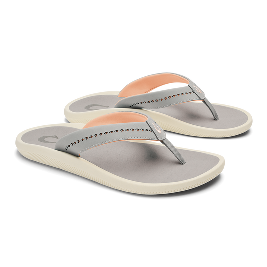 Pair of gray and cream flip-flop sandals with studded straps and peach-colored heel accents.