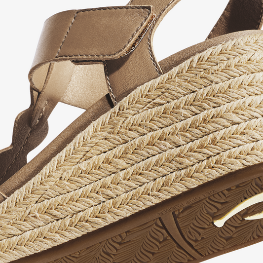 Tan leather sandal with woven jute strap and textured brown sole, shown from side detail view.