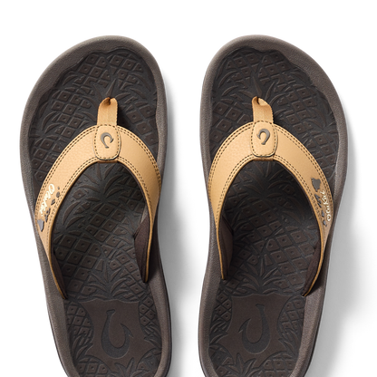 Tan and black thong sandals with decorative stitching and textured footbed, shown from above.