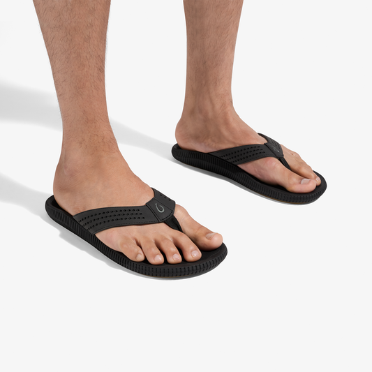 Black flip-flop sandals with textured straps and sole, worn on bare feet.
