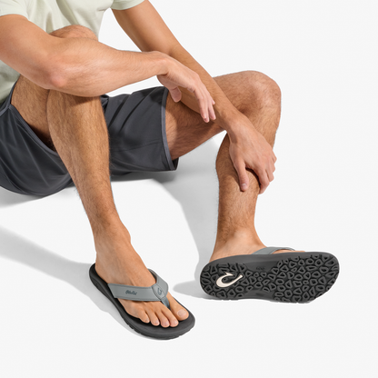 Man wearing ash and rock colored flip-flop sandal with textured sole and toe strap.