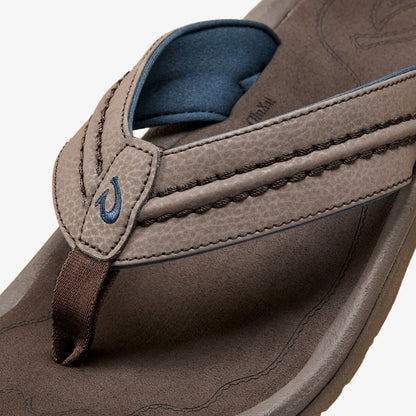 Dark brown leather thong sandal with blue teal toe post and interior lining, featuring stitched details and logo accent.