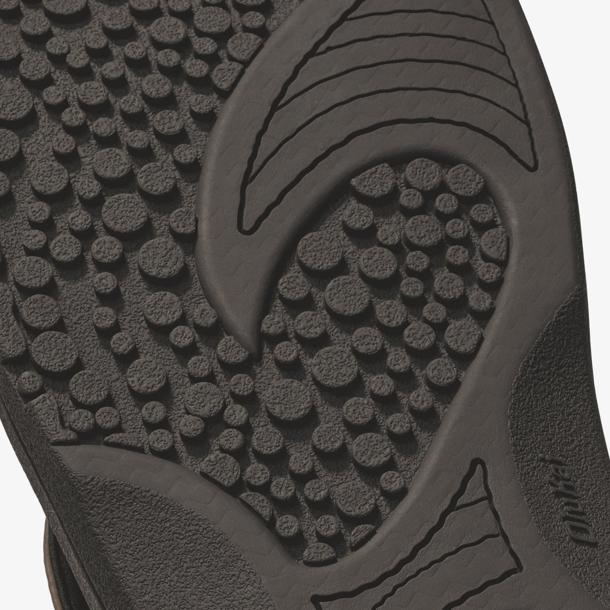 Dark textured sole of slide sandal with raised circular tread pattern and curved grip lines.