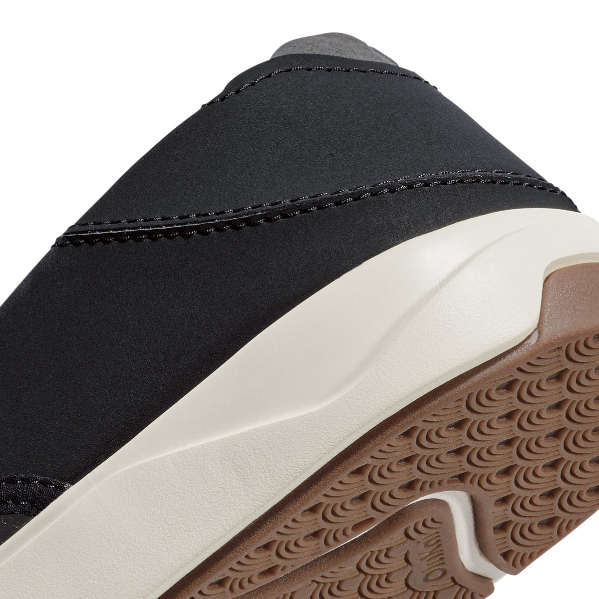 Black fabric upper with stitched trim detail, cream and tan textured sole visible below.