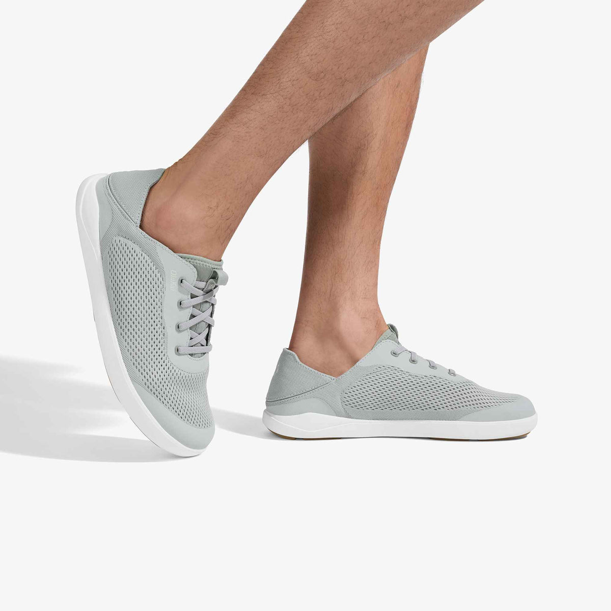 Grey mesh lace-up sneaker with white sole, shown on a man's foot from ankle down.