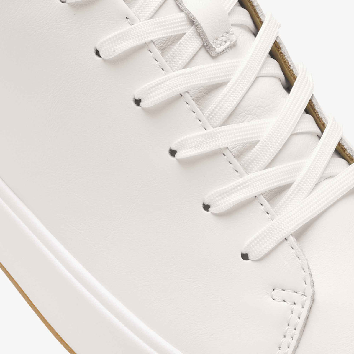 White leather high-top sneaker with white laces and tan suede heel detail, shown from overhead angle.