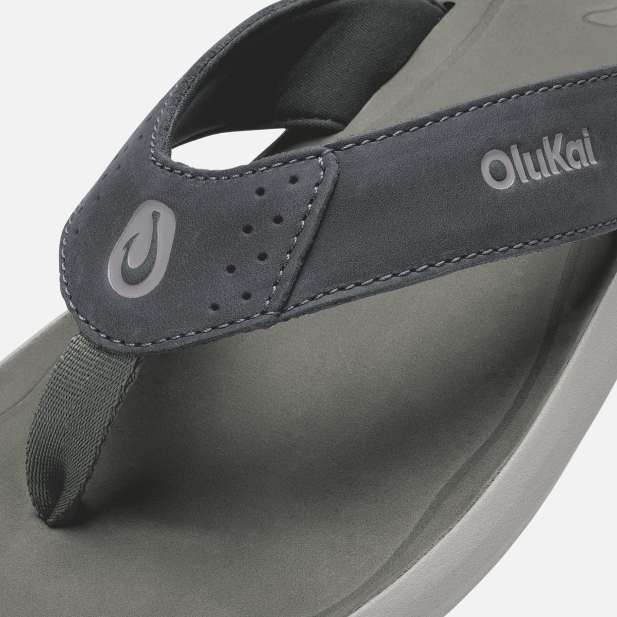 OluKai Pili thong sandal in gray and charcoal with toe post and brand logo visible.