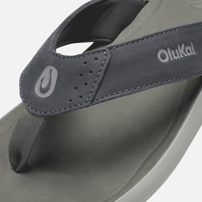 OluKai Pili thong sandal in gray and charcoal with toe post and brand logo visible.