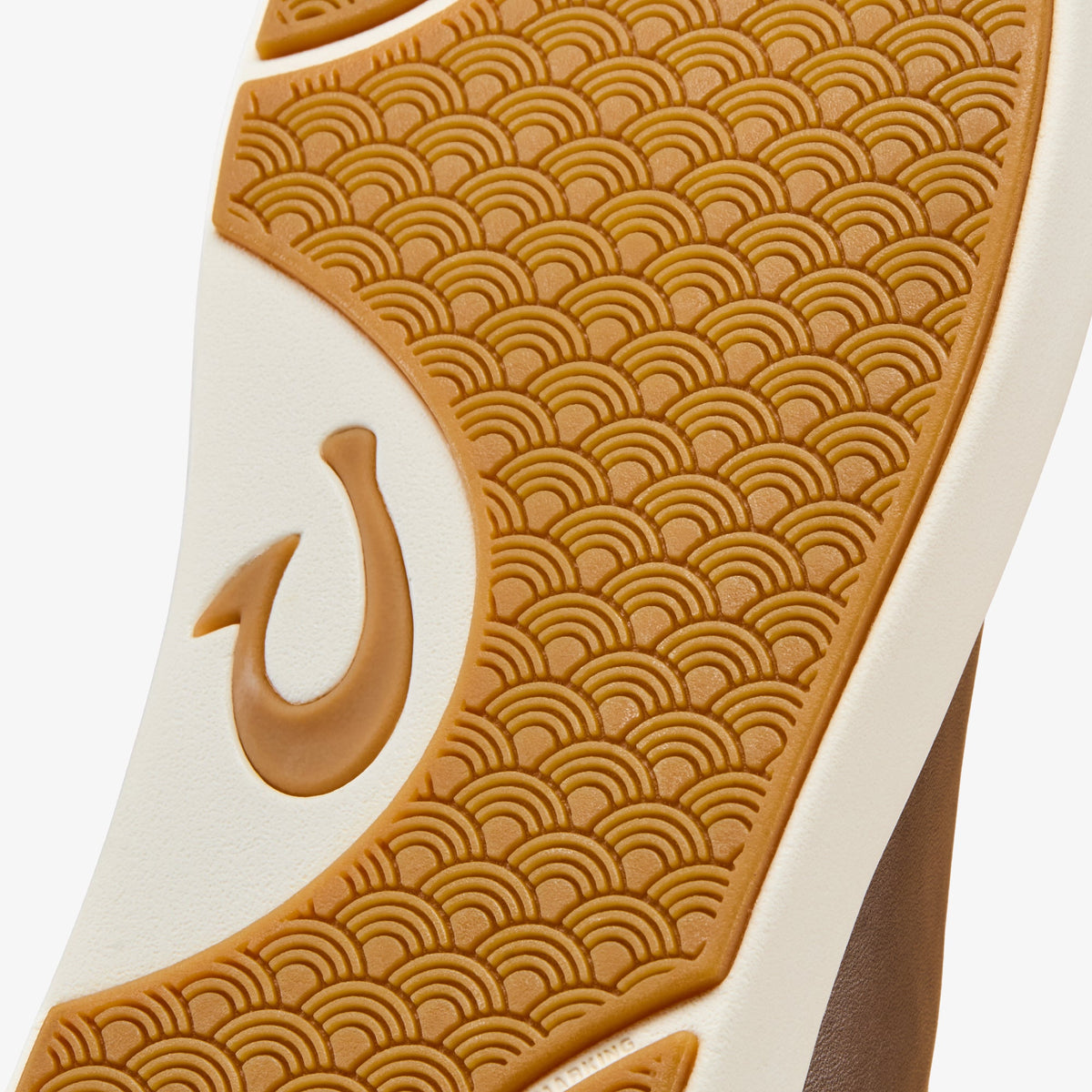 Tan and cream sneaker sole with geometric wave pattern and curved logo detail.