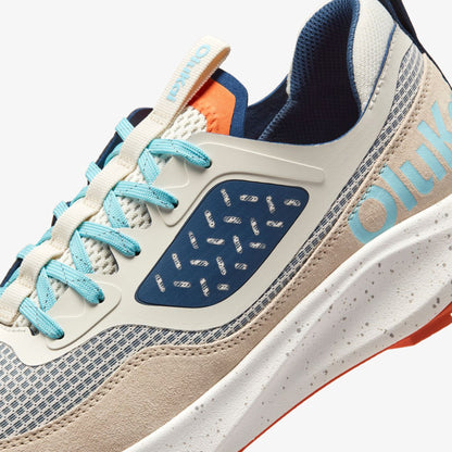 White, navy, and turquoise lace-up athletic shoe with speckled midsole and orange accent details.
