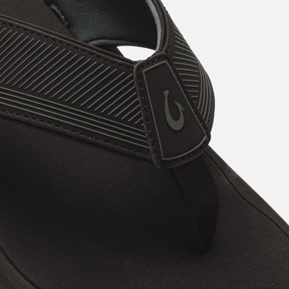 Black slide sandal with textured ribbed straps and logo patch detail on the upper.