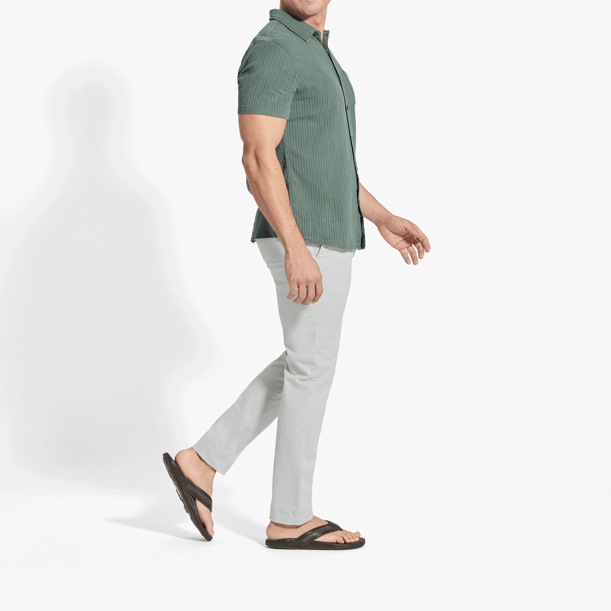 Man wearing sage green ribbed short-sleeve button-up shirt with white pants and black sandals.