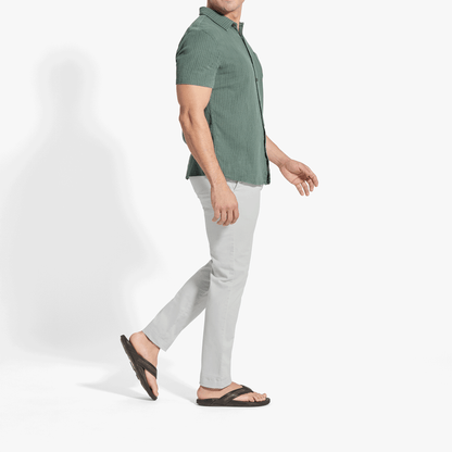 Man wearing sage green ribbed short-sleeve button-up shirt with white pants and black sandals.