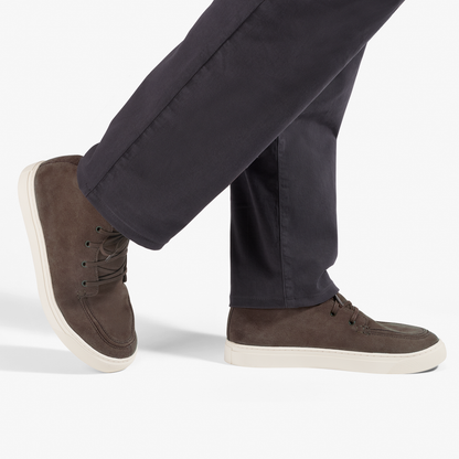 Dark brown suede chukka boots with cream-colored soles worn with dark navy pants.