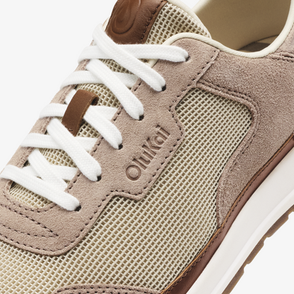 Beige and taupe suede sneaker with mesh panels, white laces, and brown heel detail.