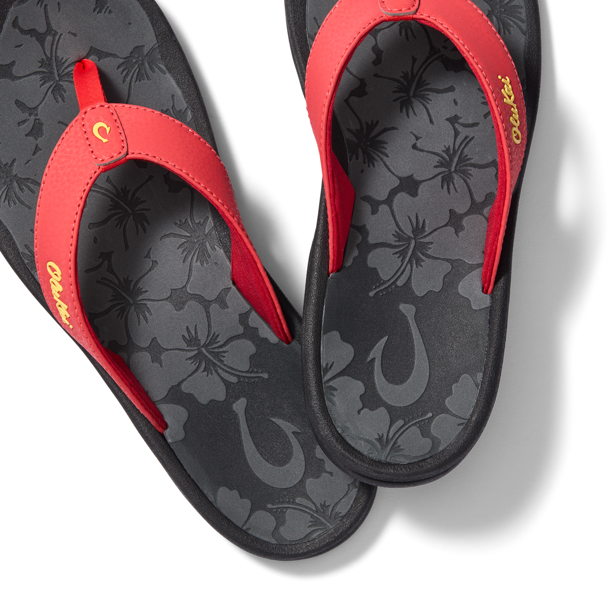 Red and black flip-flops with floral insole pattern and script text on the straps.