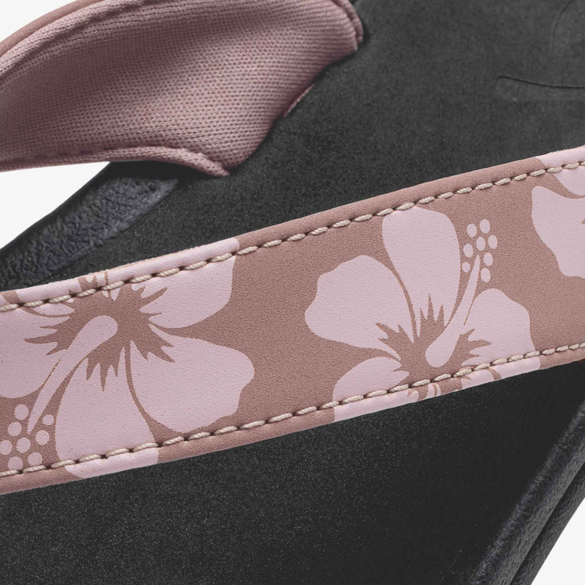 Coral rose and black footwear with floral patterned strap detail and stitched edging.