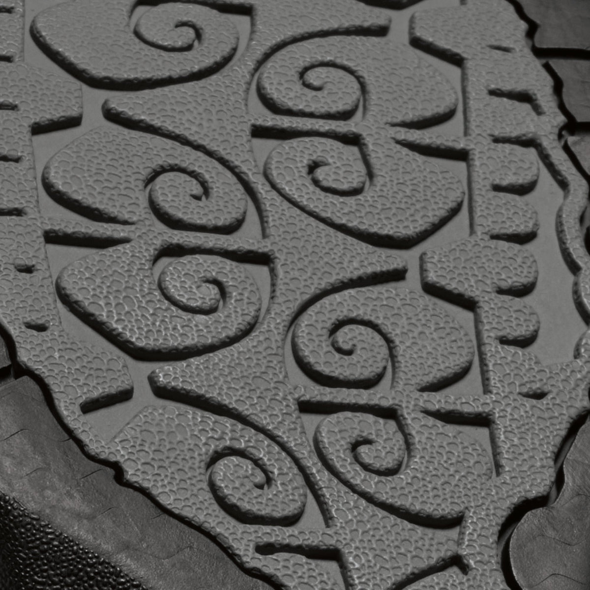 Rubber sole with repeating spiral pattern and textured surface in gray and black tones.