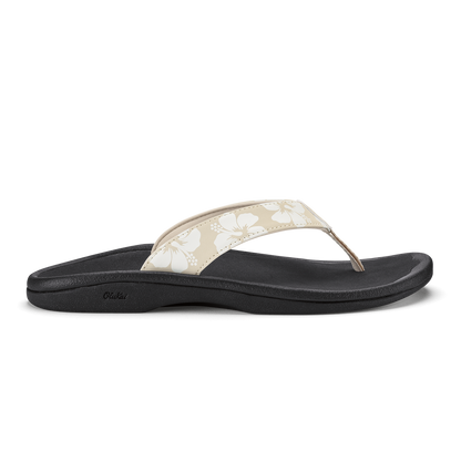 Black flip-flop sandal with beige thong strap featuring white floral pattern and dotted design.