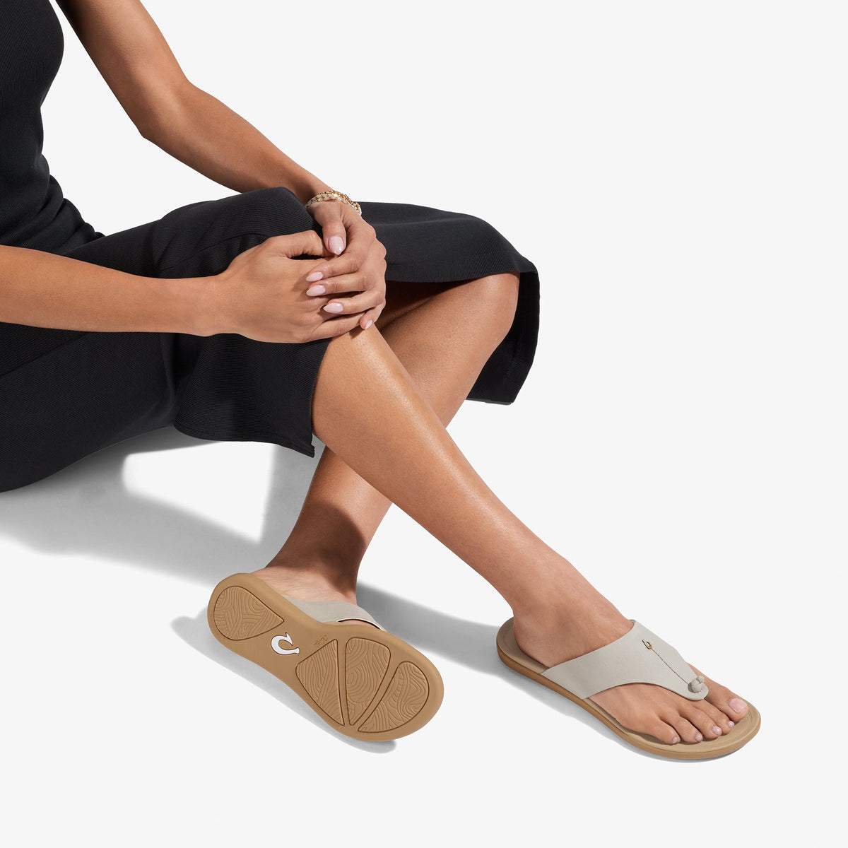 Person wearing warm sand-colored slide sandals with tan sole and cream upper strap.