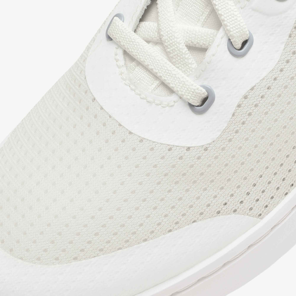 White canvas sneaker with perforated mesh upper, white laces, and gray metal eyelets.