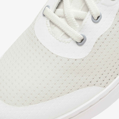 White canvas sneaker with perforated mesh upper, white laces, and gray metal eyelets.