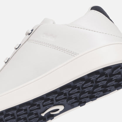 White leather sneaker with dark blue heel panel and patterned dark blue sole, featuring side stitching detail.
