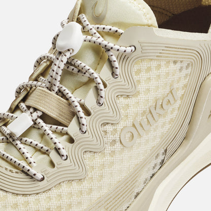White and tan sneaker with striped laces, textured upper, and wavy sole detail with brand name.