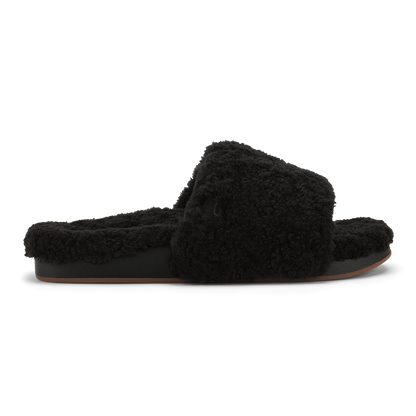 Black fuzzy slip-on slipper with cushioned sole and fluffy upper, shown in profile view.