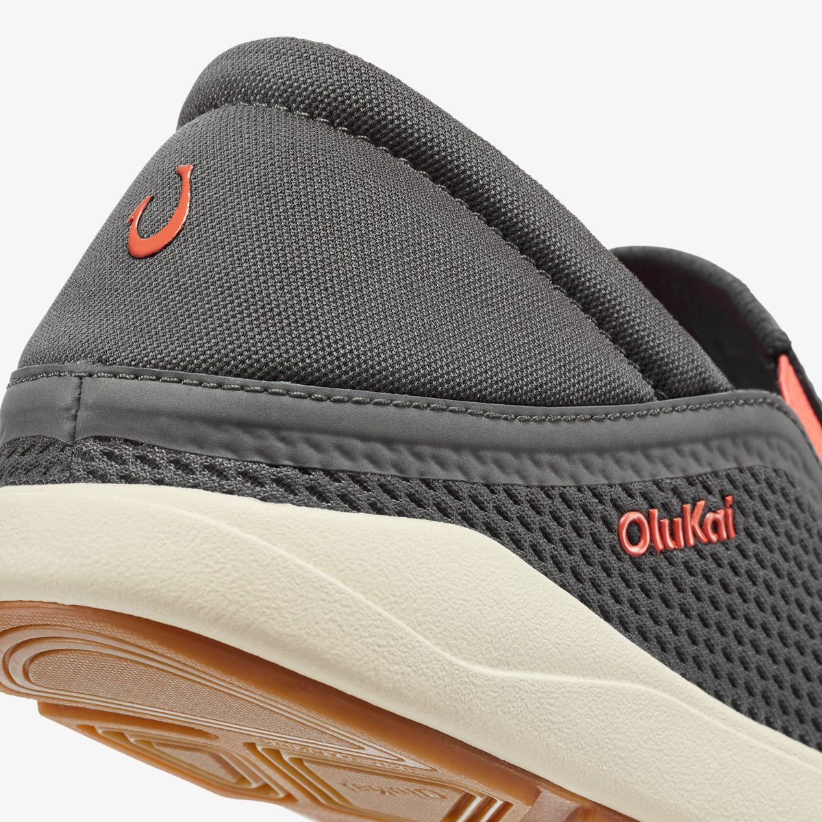 Gray mesh slip-on shoe with orange accents, cream sole, and Olukai branding on heel.