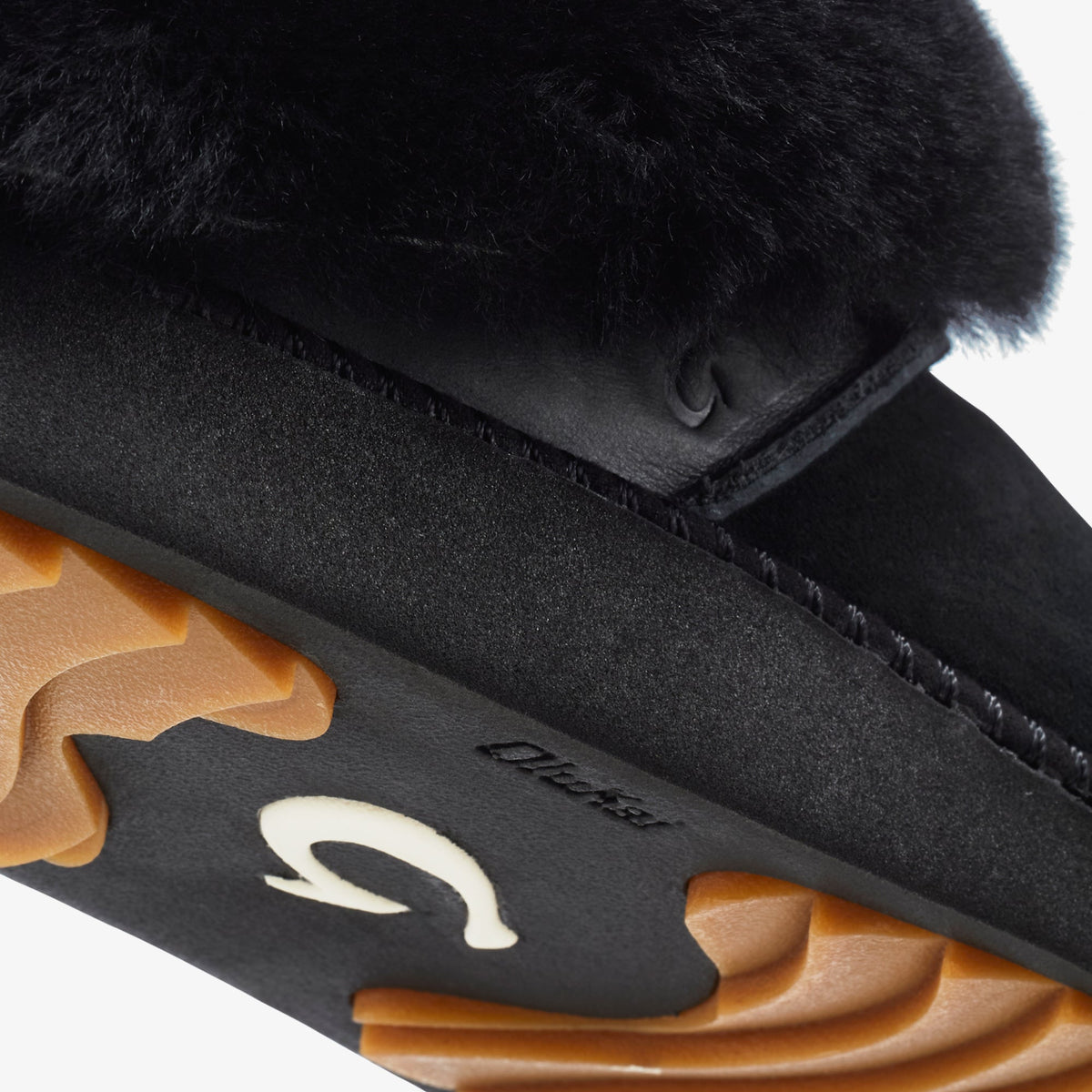 Black suede slipper with fur cuff collar, tan leather sole, and white logo detail.